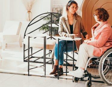 woman speaking with woman sitting in wheelchair