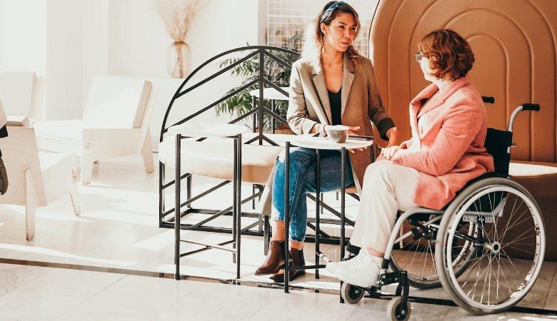 woman speaking with woman sitting in wheelchair