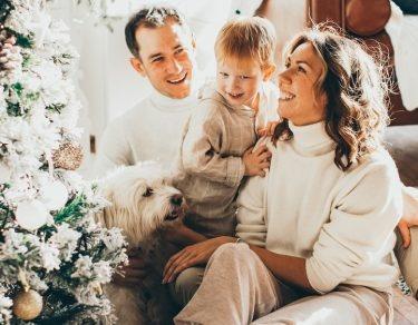 family of 3 sitting in front of christmas tree