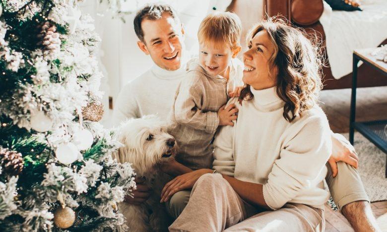 family of 3 sitting in front of christmas tree