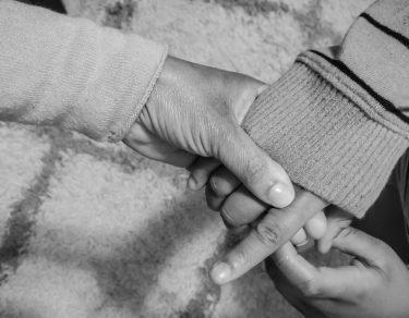 black and white photo of mother lovingly holds child's hand