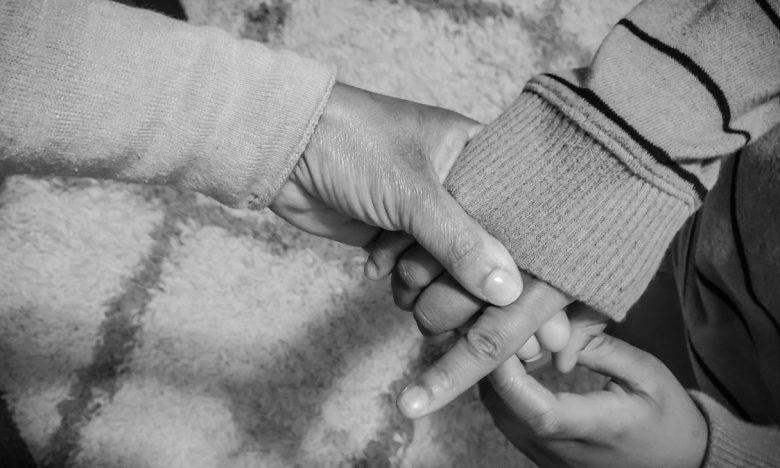 black and white photo of mother lovingly holds child's hand