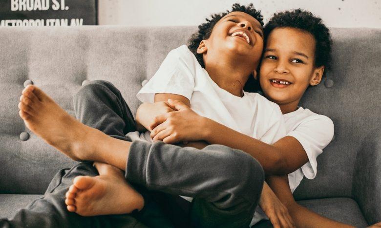 brother wraps legs around sibling while they both laugh