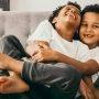 brother wraps legs around sibling while they both laugh