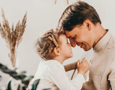 dad looks into daughter's eyes while both smile