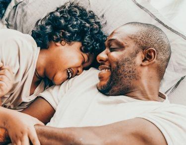 dad laughs with 2 sons while in bed