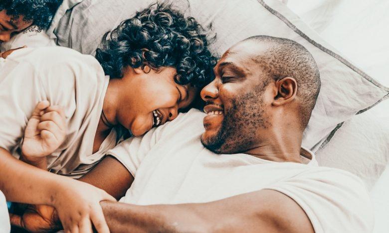 dad laughs with 2 sons while in bed