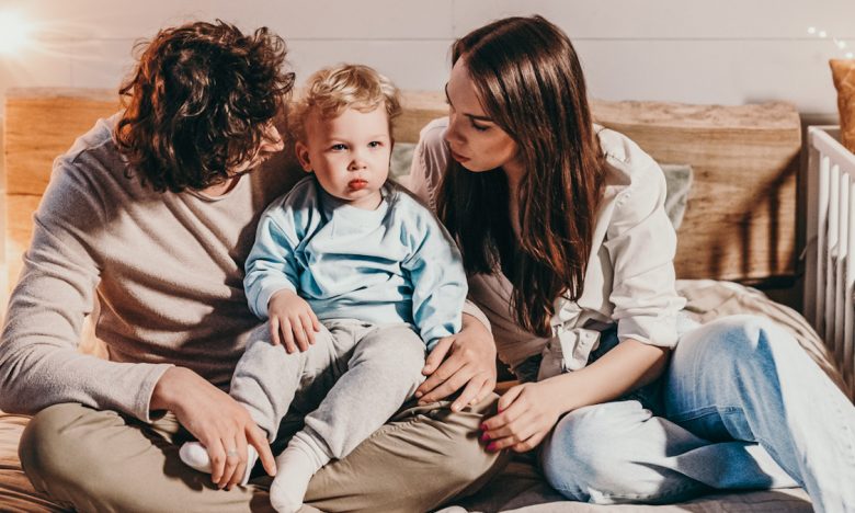 parents sitting on floor while looking at toddler