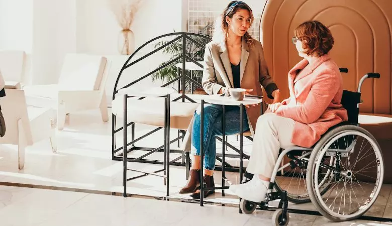 woman speaking with woman sitting in wheelchair