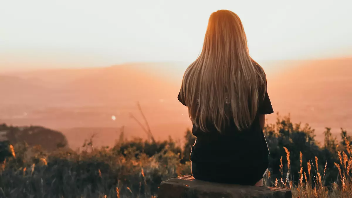 young woman sitting on rock watching sunset