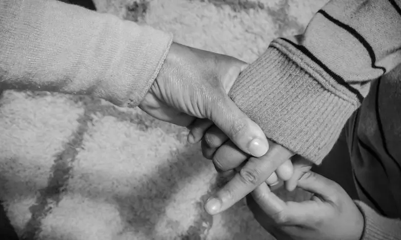 black and white photo of mother lovingly holds child's hand
