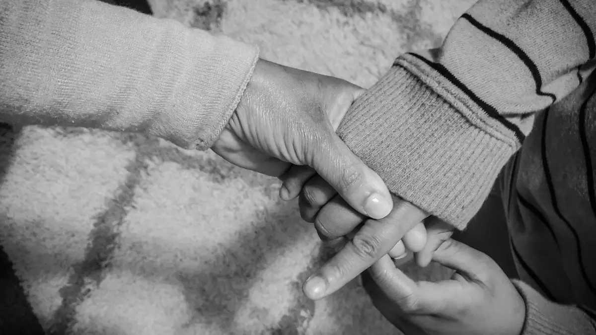 black and white photo of mother lovingly holds child's hand