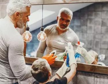 Father and son cleaning mirror