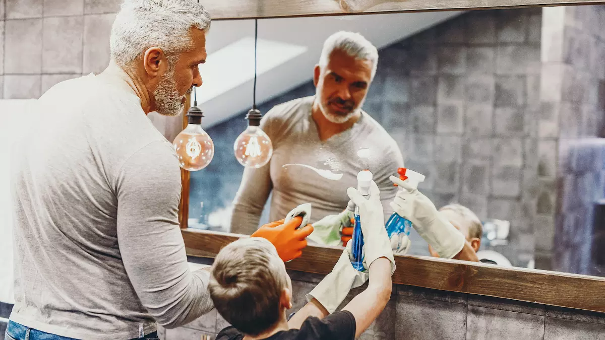 Father and son cleaning mirror