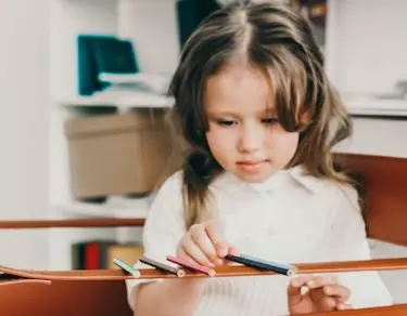 special needs girl sharpening pencil in session