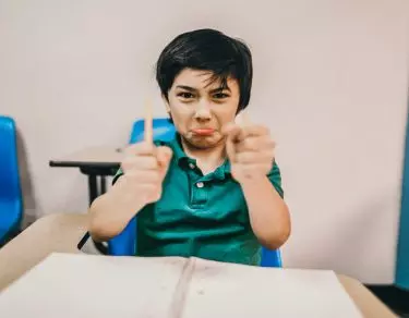 angry boy in classroom breaks pencil in half