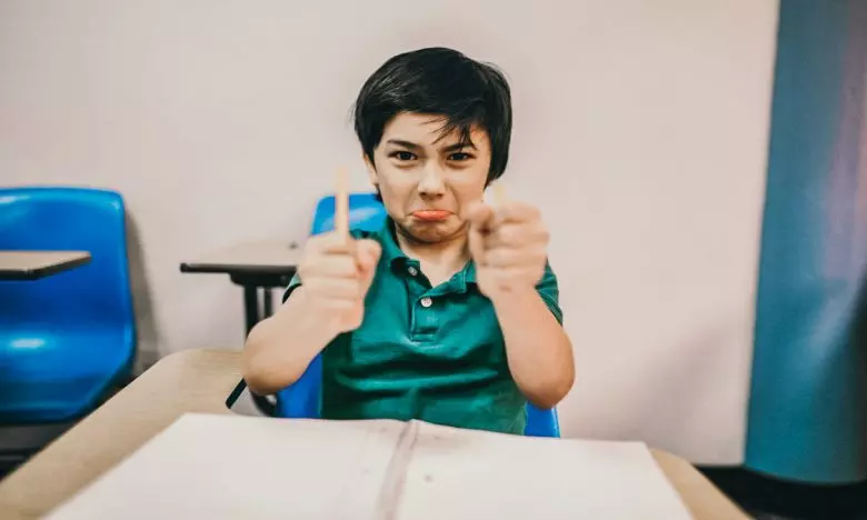 angry boy in classroom breaks pencil in half