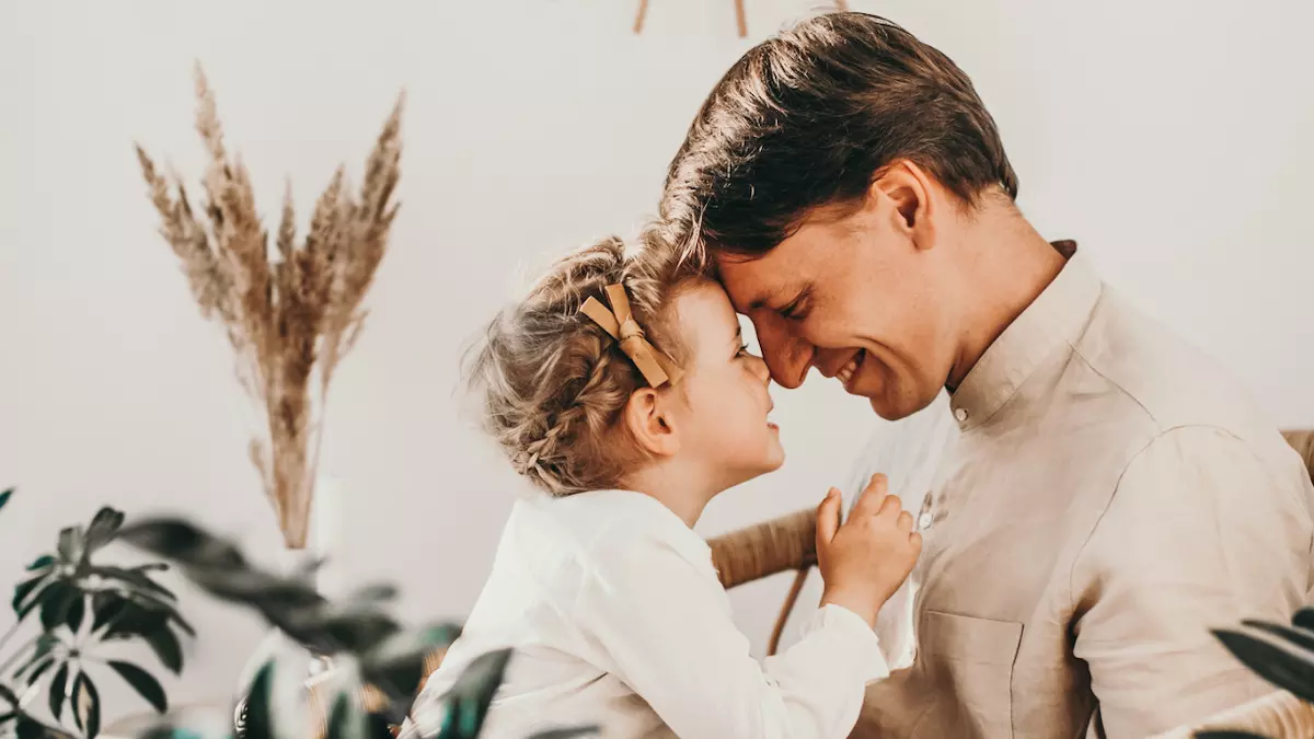 dad looks into daughter's eyes while both smile