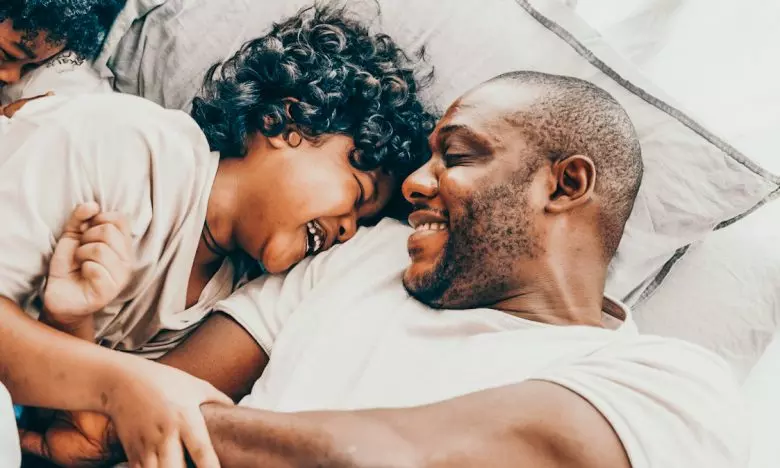 dad laughs with 2 sons while in bed