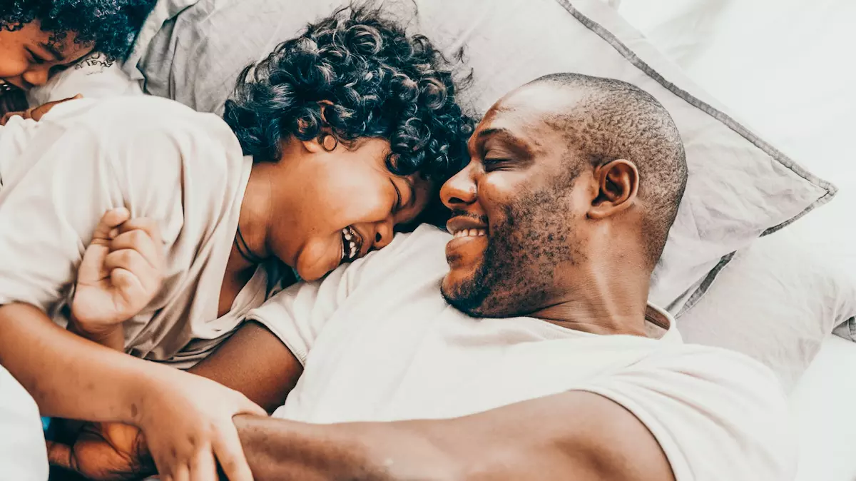 dad laughs with 2 sons while in bed